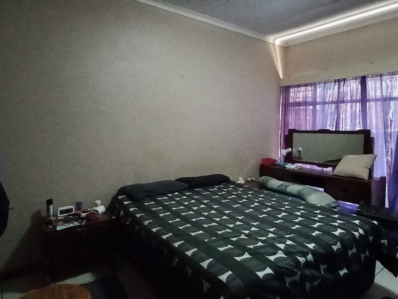 A standard bedroom featuring tiled flooring, cove cornicing, and a large window allowing natural light into the space.