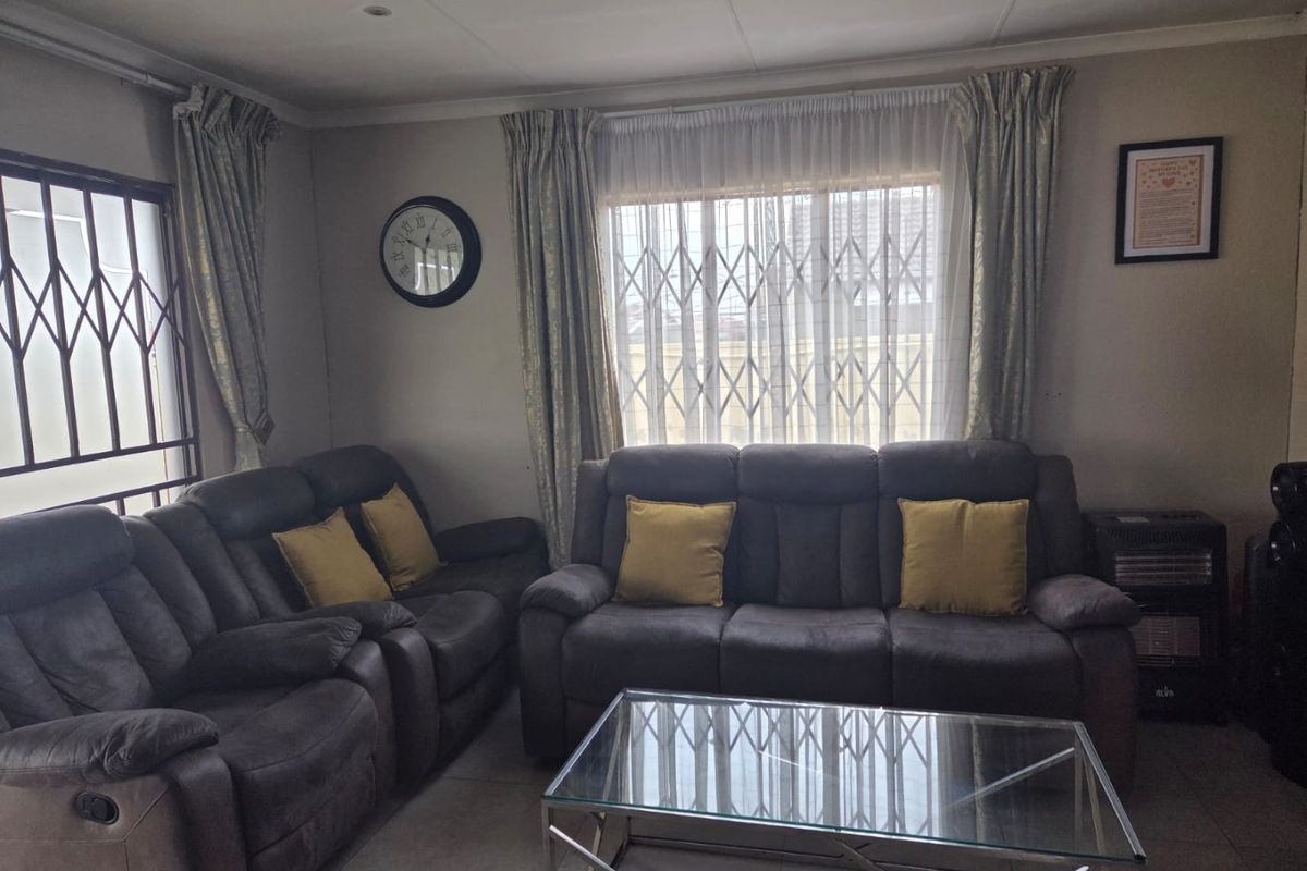 A comfortable living room featuring tiled flooring and security gates on the windows, providing a functional and secure space for relaxation.