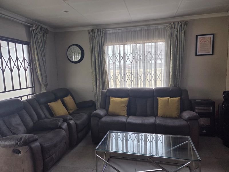 A comfortable living room featuring tiled flooring and security gates on the windows, providing a functional and secure space for relaxation.