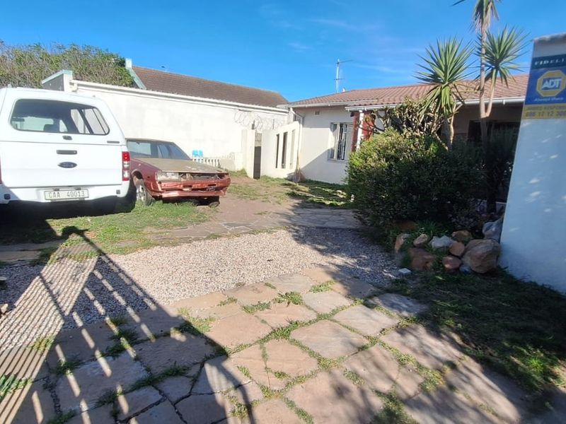 Front exterior view of the property featuring a paved driveway, boundary wall, and security alarm signage.