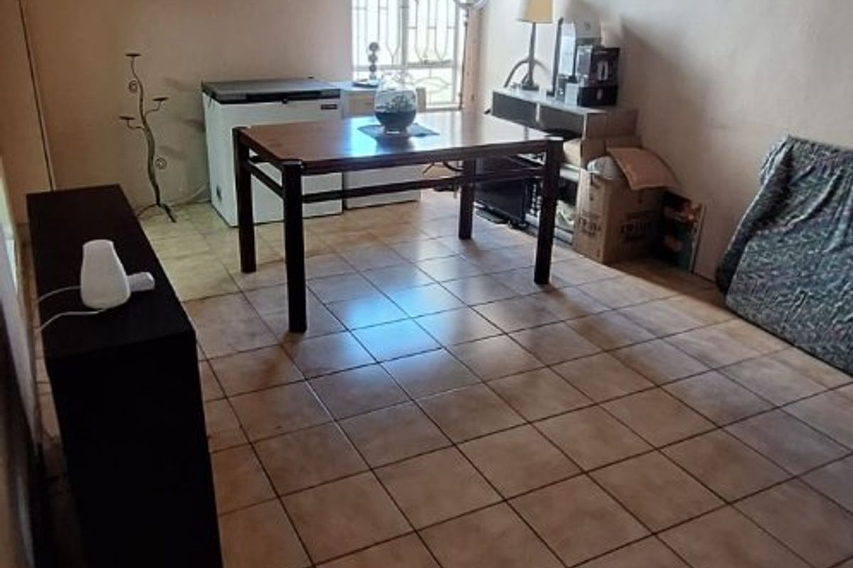 A living area featuring tiled flooring, a timber-clad ceiling with a fan, and a window fitted with a security gate.