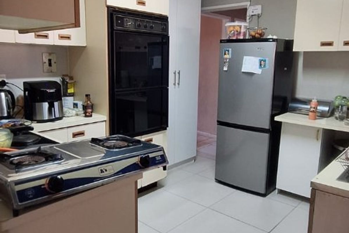 A functional kitchen featuring built-in oven, tiled flooring, and ample cabinetry, offering a practical layout with potential for modern cosmetic updates.