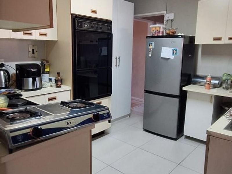 A functional kitchen featuring built-in oven, tiled flooring, and ample cabinetry, offering a practical layout with potential for modern cosmetic updates.