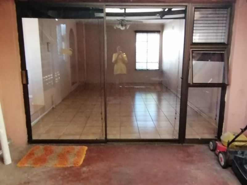 Covered patio area featuring tiled flooring, exposed rafters, and a large sliding glass door leading into the interior living space.
