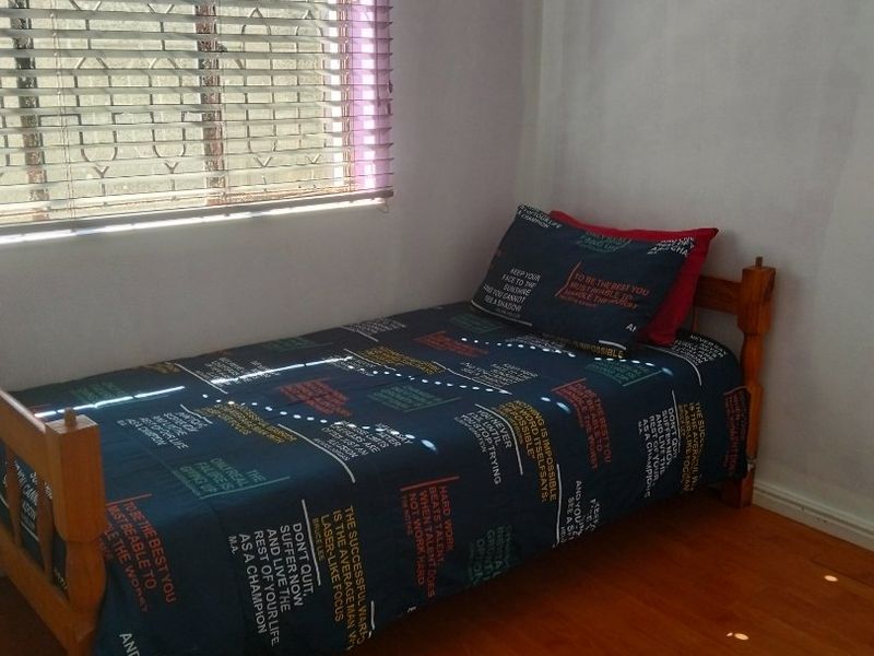 A compact bedroom featuring laminate flooring and venetian blinds, providing a functional and neutral space.