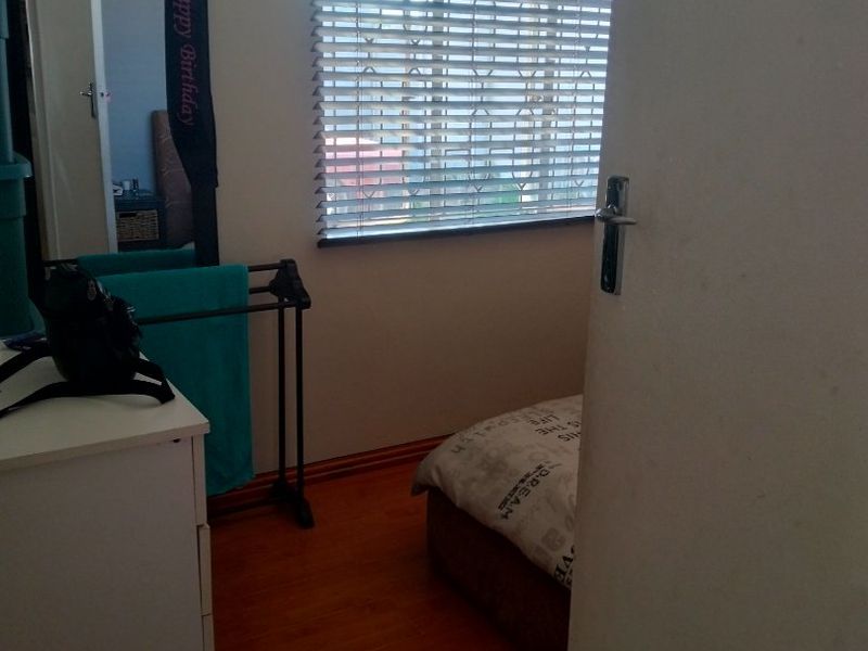 A bedroom featuring laminate flooring, venetian blinds, and neutral wall finishes, viewed from the doorway.