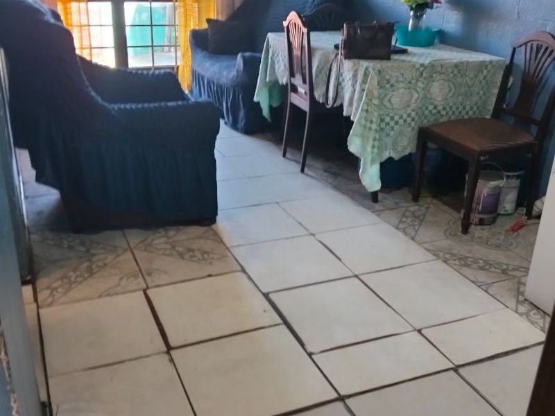 A living room area featuring tiled flooring and a sliding glass door providing natural light.
