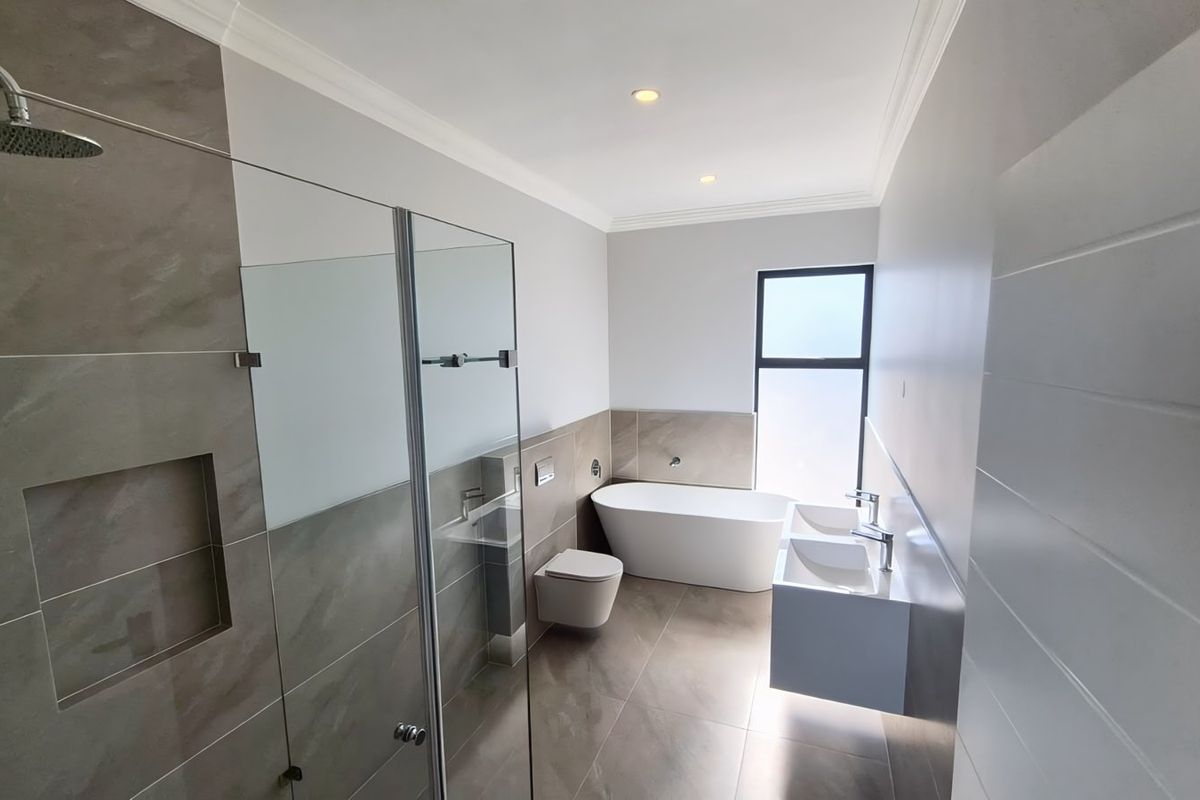 Modern, well-appointed bathroom featuring a freestanding bathtub, wall-hung toilet, double vanity, and a spacious walk-in shower with contemporary tiling.
