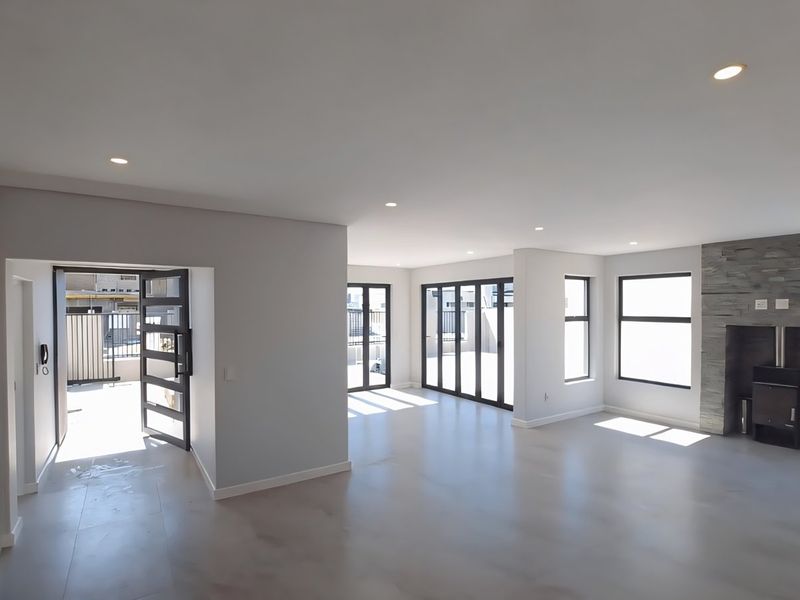 Spacious open-plan living area featuring modern tiled floors, recessed lighting, and a striking stone-clad fireplace with a built-in wood-burning stove.