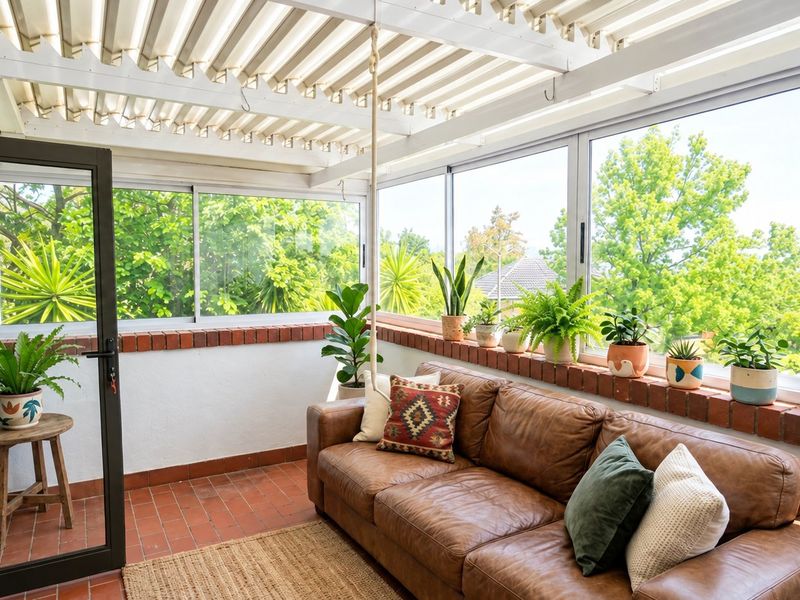 A bright, enclosed patio featuring a louvred roof, sliding glass windows, and classic brick detailing, offering a comfortable space with garden views.