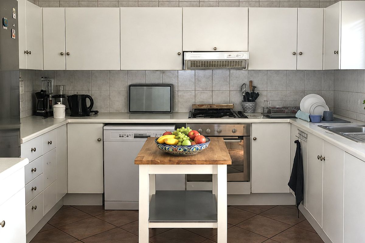 A functional kitchen featuring white cabinetry, tiled backsplash, stainless steel oven with gas cooktop, and a double bowl sink.