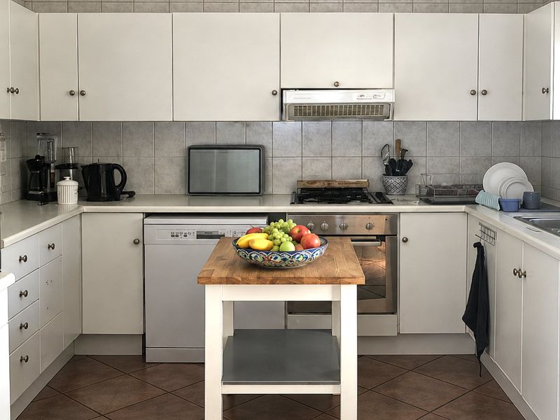 A functional kitchen featuring white cabinetry, tiled backsplash, stainless steel oven with gas cooktop, and a double bowl sink.