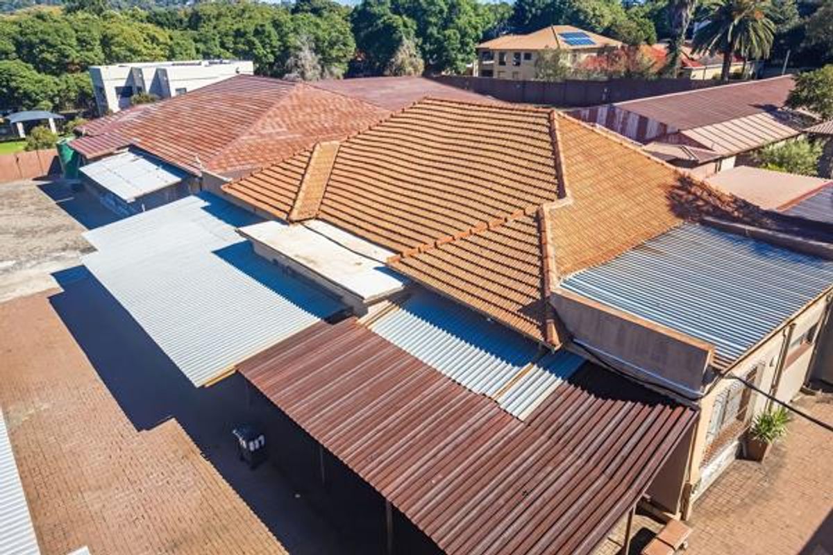 Aerial view of the commercial property showing multiple roof structures, including tiled and corrugated metal sections, with paved exterior areas.
