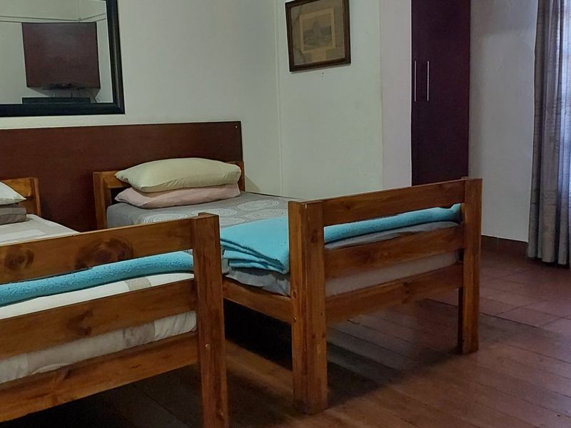A bedroom featuring wooden flooring and a built-in wardrobe, providing a functional space with natural light from the window.