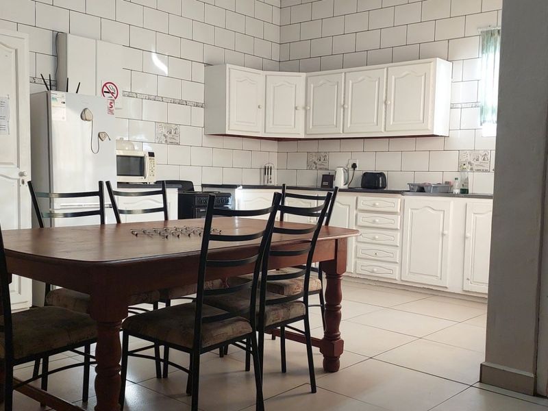Open-plan kitchen and dining area featuring white cabinetry, tiled backsplash, and tiled flooring, offering a functional layout for daily living.
