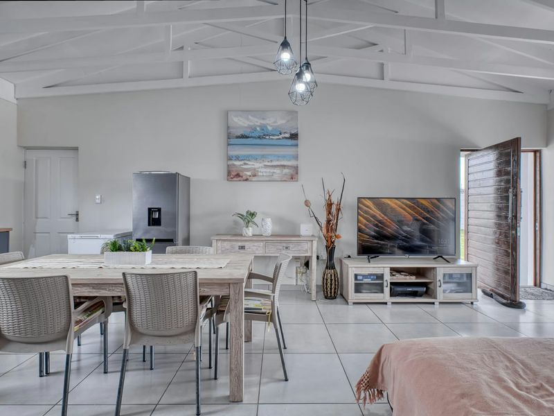 Spacious open-plan living and dining area featuring high vaulted ceilings with exposed white timber trusses and neutral tiled flooring throughout.