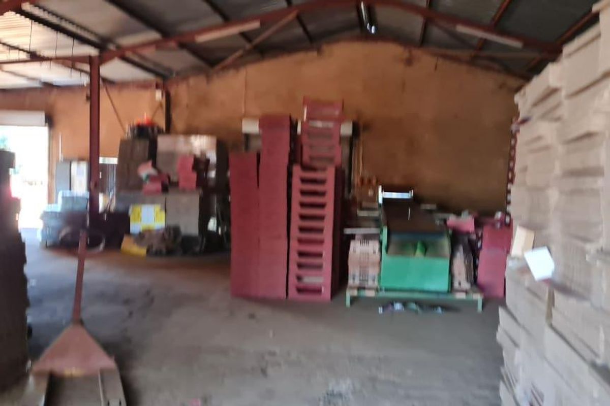 A large industrial utility space or storage shed featuring a high corrugated metal roof, steel structural framing, and concrete flooring.