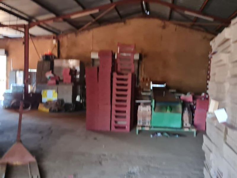 A large industrial utility space or storage shed featuring a high corrugated metal roof, steel structural framing, and concrete flooring.
