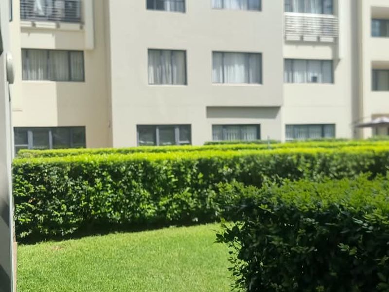 A view of the apartment building exterior featuring a well-maintained lawn and manicured garden hedges.
