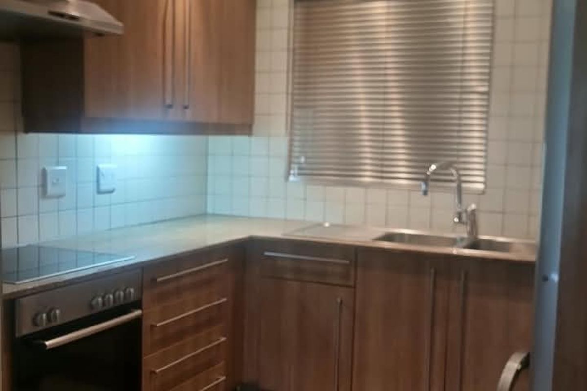 A functional kitchen featuring wood-finish cabinetry, integrated appliances, tiled backsplash, and recessed lighting, providing a practical and well-maintained cooking space.