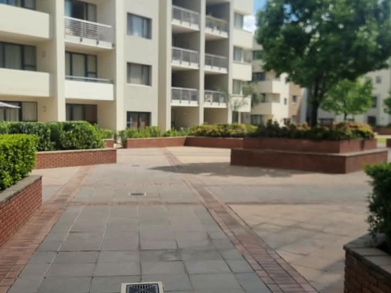 A view of the apartment complex exterior featuring paved courtyard areas, brick planter boxes, and multi-level balconies.