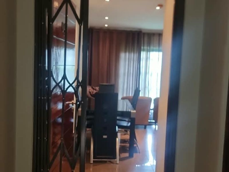 A view through a security gate into an interior living space featuring tiled flooring and recessed downlighting.