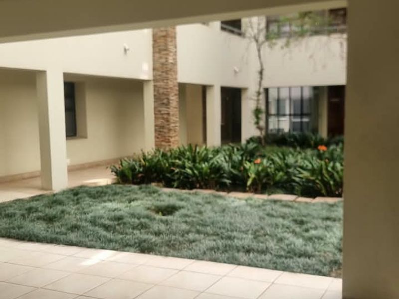 A covered patio area overlooking a central landscaped courtyard with stone-clad architectural features and tiled flooring.