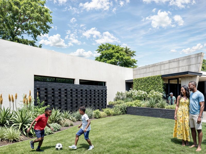 A modern rear garden featuring a manicured lawn, structured landscaping, and a contemporary architectural facade with a black brick feature wall.