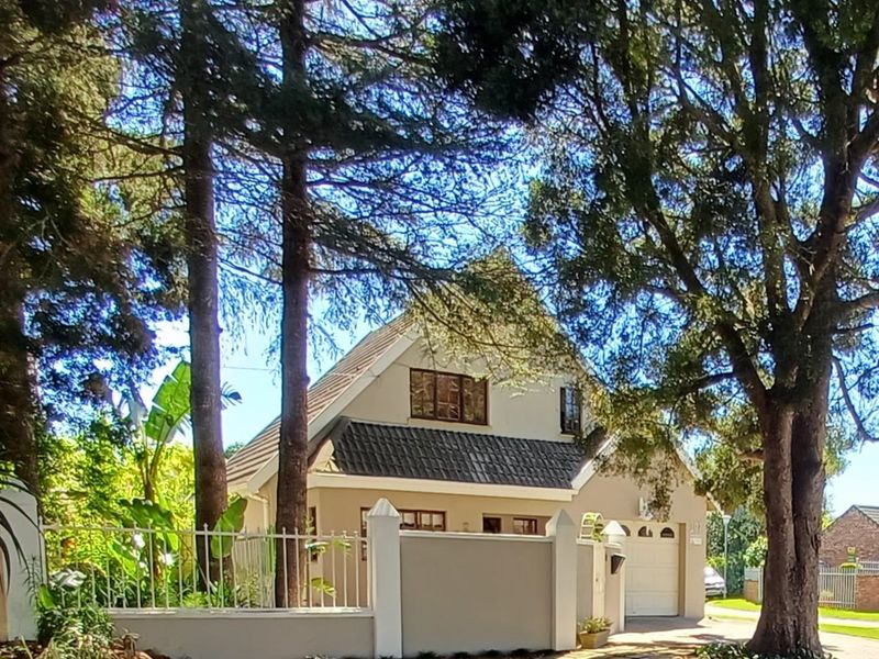 Front view of a residential house featuring a tiled roof, integrated garage, and a secure boundary wall with metal fencing.