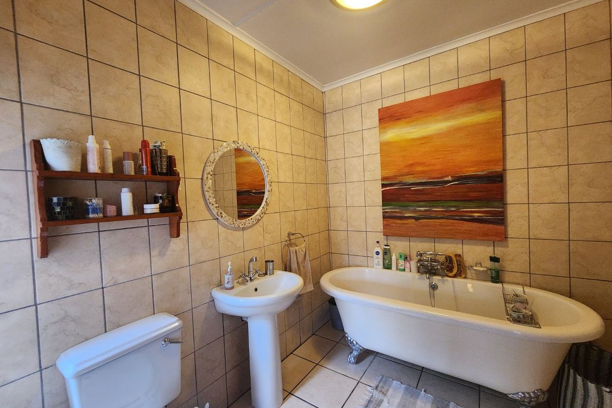 A functional bathroom featuring a classic clawfoot bathtub, pedestal washbasin, and neutral ceramic tiling throughout.