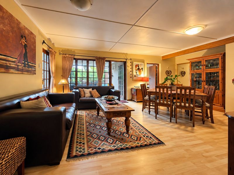 Spacious open-plan living and dining area featuring laminate flooring, timber-framed glass doors leading to the patio, and a built-in display cabinet.