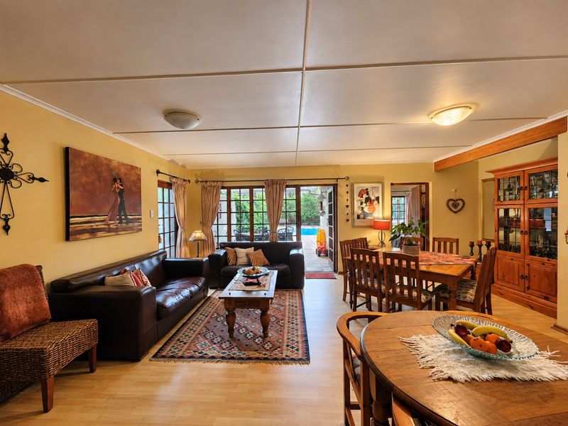 Spacious open-plan living and dining area featuring laminate flooring, built-in timber cabinetry, and direct access to the outdoor patio and pool area.