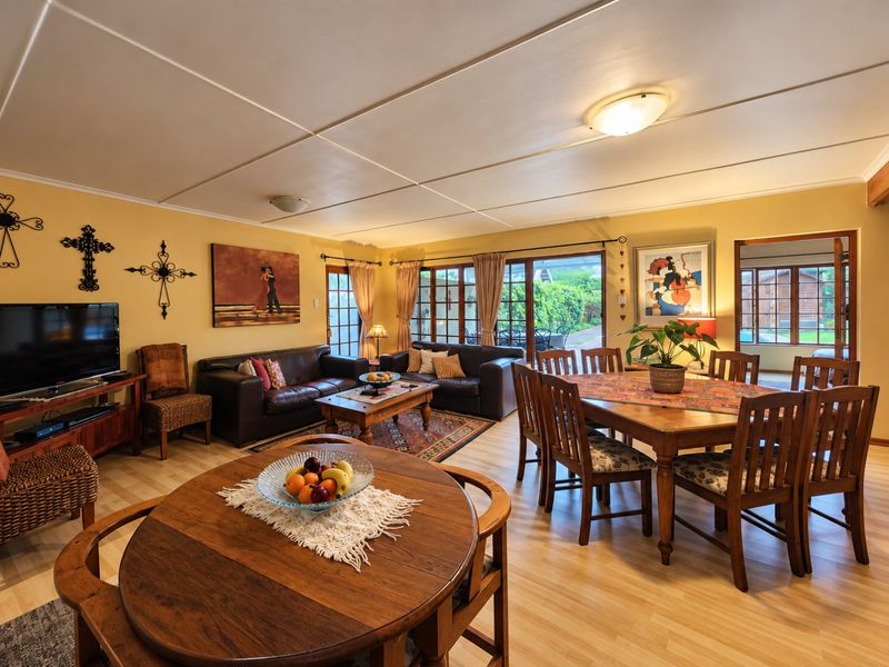Spacious open-plan living and dining area featuring laminate flooring, neutral walls, and large sliding glass doors providing access to the outdoor patio.