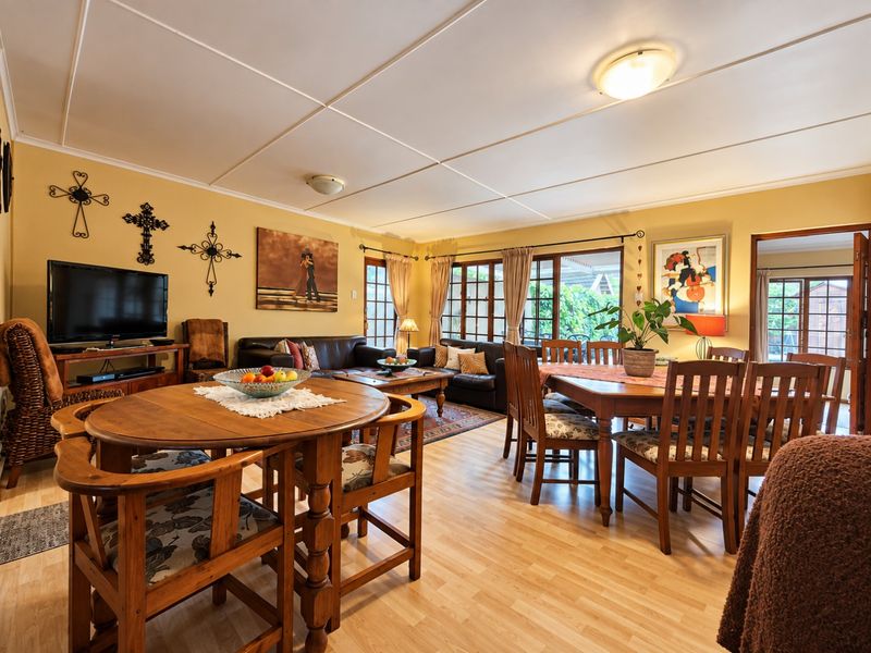 Spacious open-plan living and dining area featuring laminate flooring, panelled ceilings, and large sliding glass doors providing access to the outdoor space.
