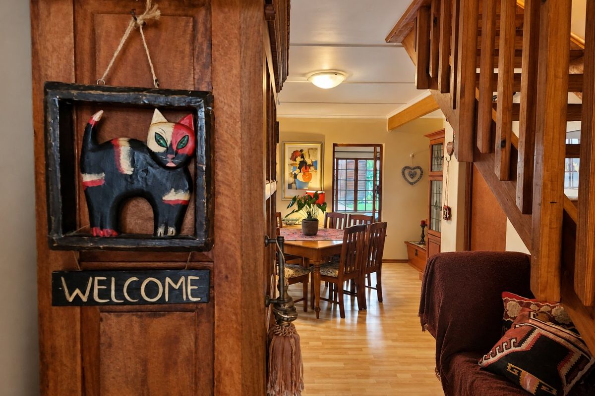 A view from the entryway looking into the dining area, featuring a wooden staircase and laminate flooring throughout the open living space.