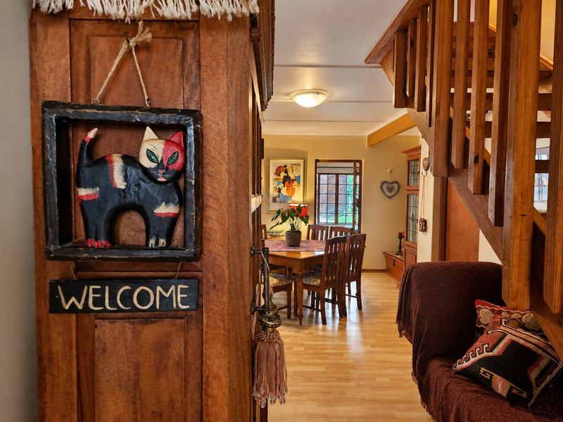 A view from the entryway looking into the dining area, featuring a wooden staircase and laminate flooring throughout the open living space.