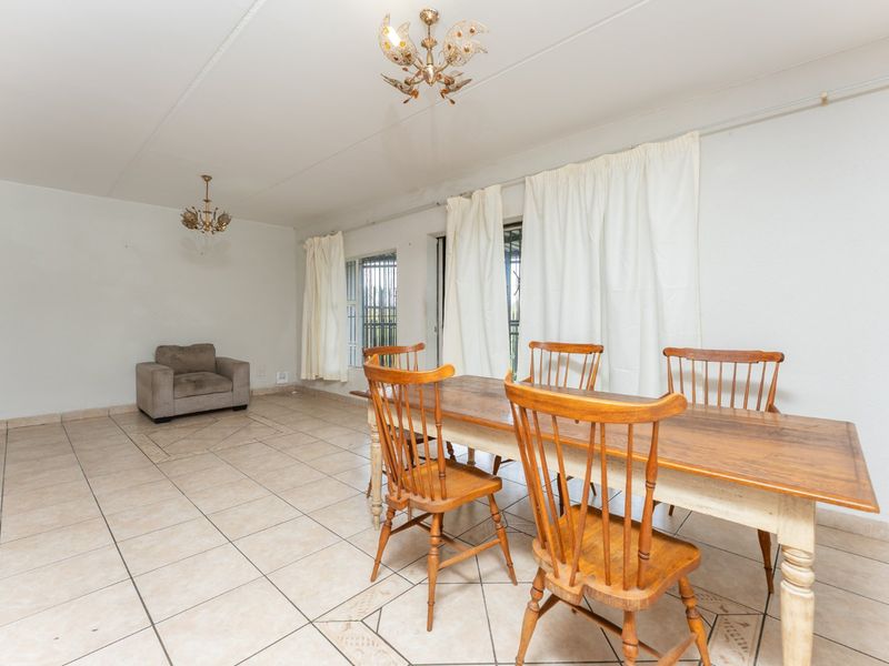 A spacious dining area featuring tiled flooring and dual ceiling light fixtures, offering a blank canvas for potential interior updates.