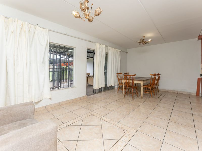 Open plan living and dining area featuring tiled flooring, direct access to an outdoor patio, and a compact kitchen corner.