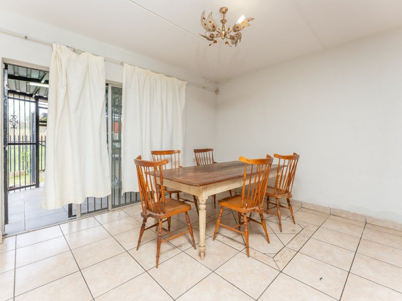 Dining area featuring tiled flooring and a sliding glass door with security gate providing access to the outdoor space.