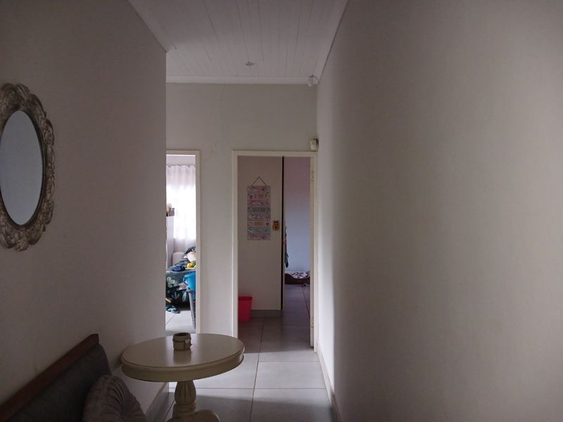 A functional hallway featuring tiled flooring and a tongue and groove ceiling, providing access to adjacent rooms.