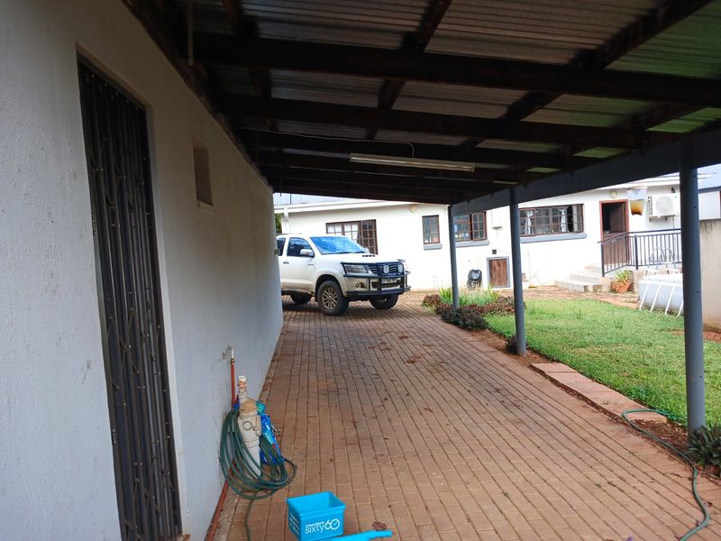 A covered outdoor patio area featuring paved flooring and direct access to the side of the property and garden.
