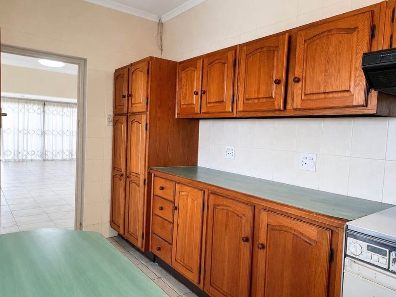 A functional kitchen featuring traditional wooden cabinetry, tiled backsplash, and laminate countertops, offering a classic layout with potential for modern updates.