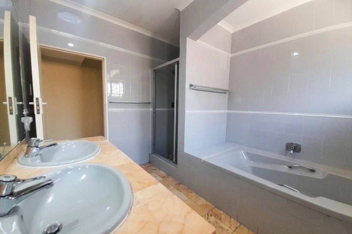 A spacious bathroom featuring a double vanity, a built-in bathtub, and a separate shower enclosure with neutral wall tiling.