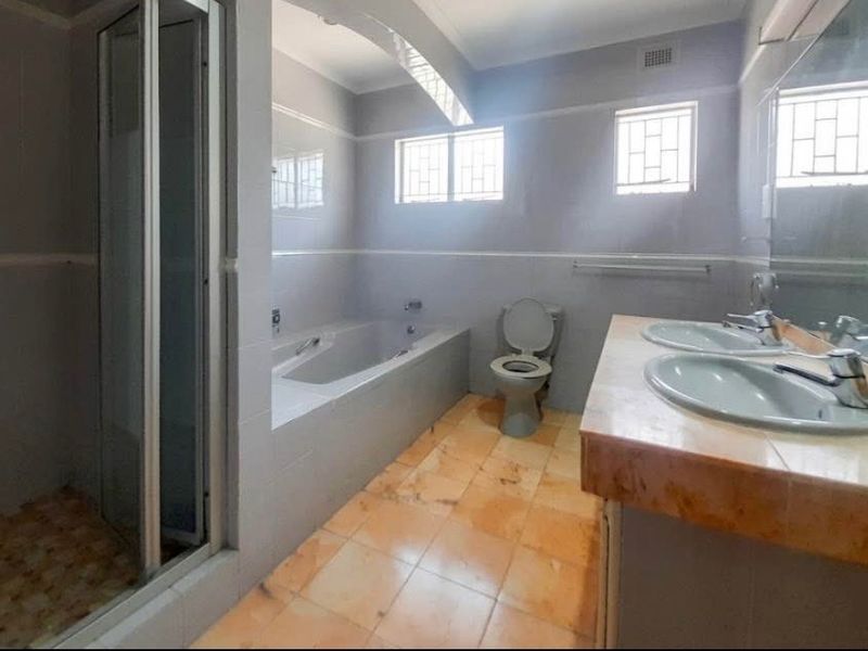 A spacious bathroom featuring a double vanity, built-in bathtub, and separate shower enclosure with neutral wall tiling and tiled flooring.