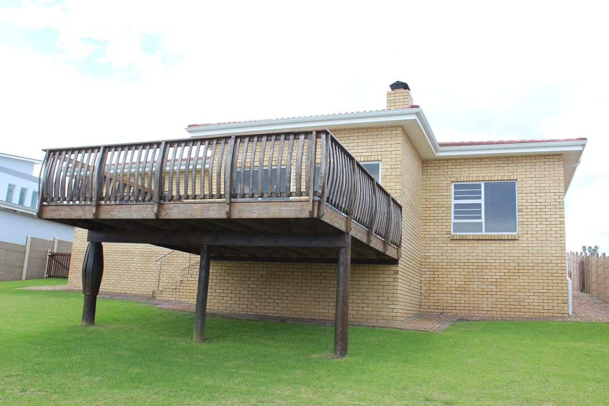 Rear view of the house featuring a raised timber deck, brick exterior walls, and a paved walkway leading to the garden.