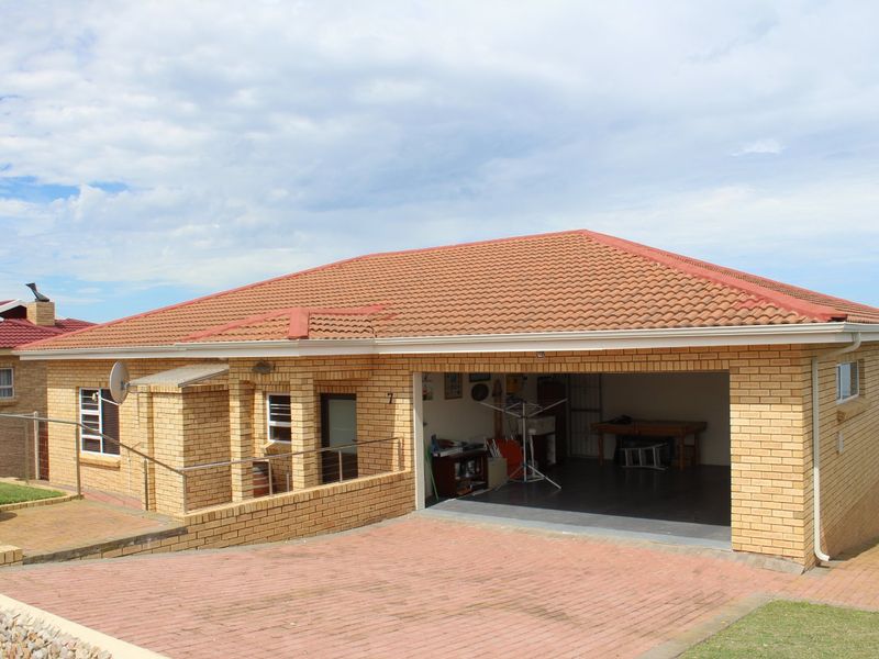 Front view of a single-story brick house featuring a tiled roof, paved driveway, and an integrated double garage.