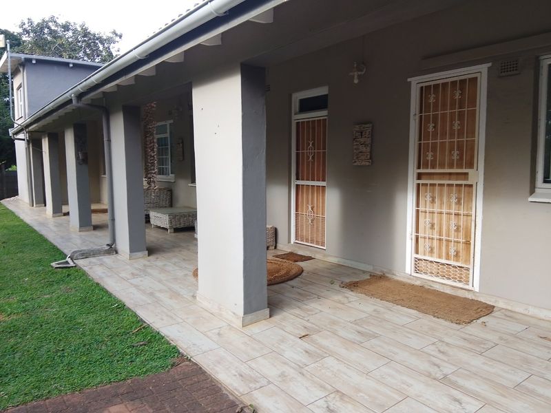 A covered patio area featuring tiled flooring, structural pillars, and secure access points leading into the home.