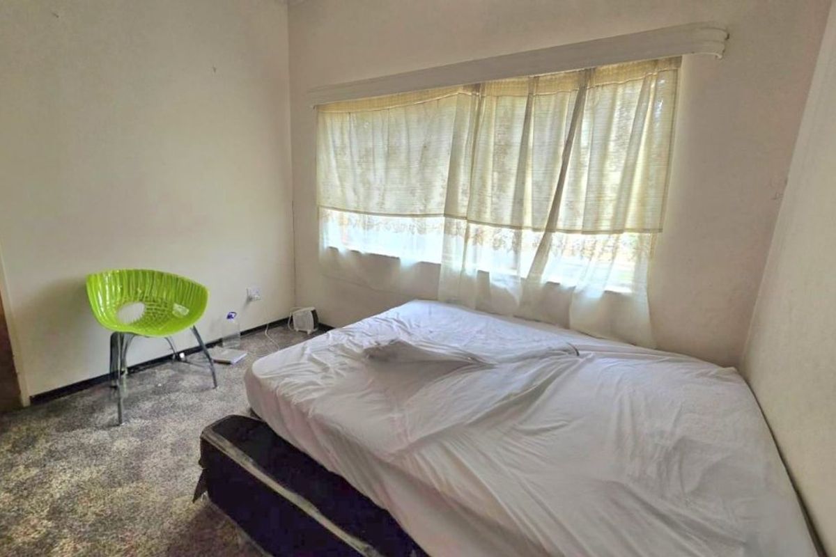 A bedroom featuring carpeted flooring and a window with a curtain rail, requiring cosmetic updates to improve its overall condition.