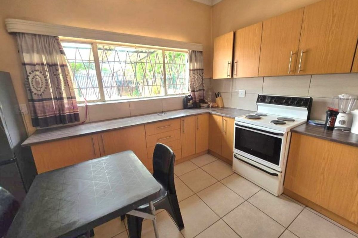A functional kitchen featuring laminate cabinetry, tiled flooring, a tiled backsplash, and a freestanding oven with hob, offering a practical layout for daily use.