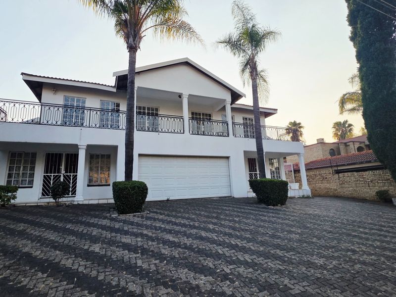 Front elevation of a two-story residence featuring a paved driveway, double garage, and an upper-level balcony with wrought iron railings.